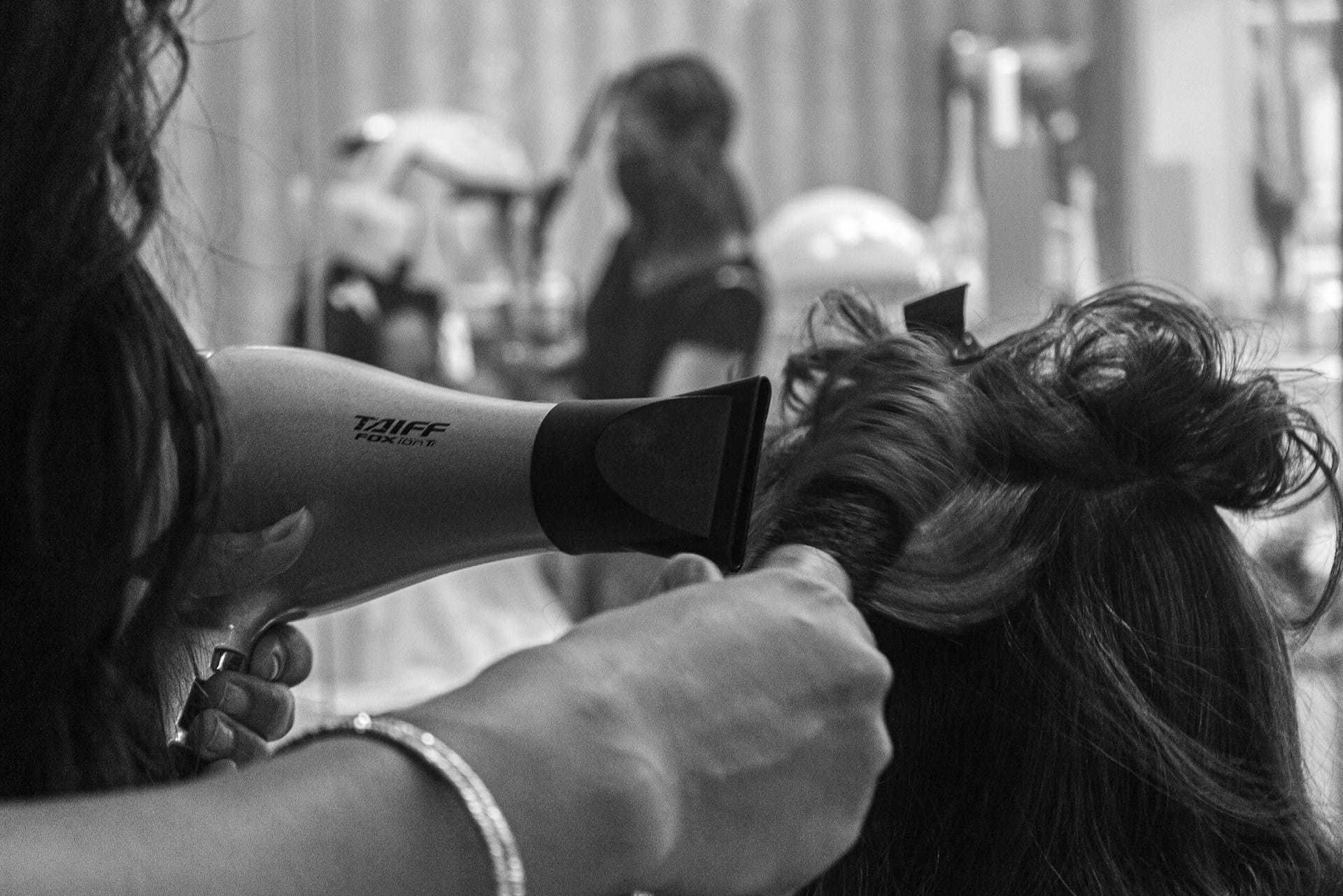 Drying hair at a salon with a blow dryer amidst styling tools.